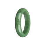 A close-up image of a beautiful, high-quality green Burmese jade bangle bracelet. The bracelet has a smooth, polished surface and is in the shape of a half moon. It measures 58mm in diameter. The vibrant green color of the jade is eye-catching and adds a touch of elegance to any outfit.