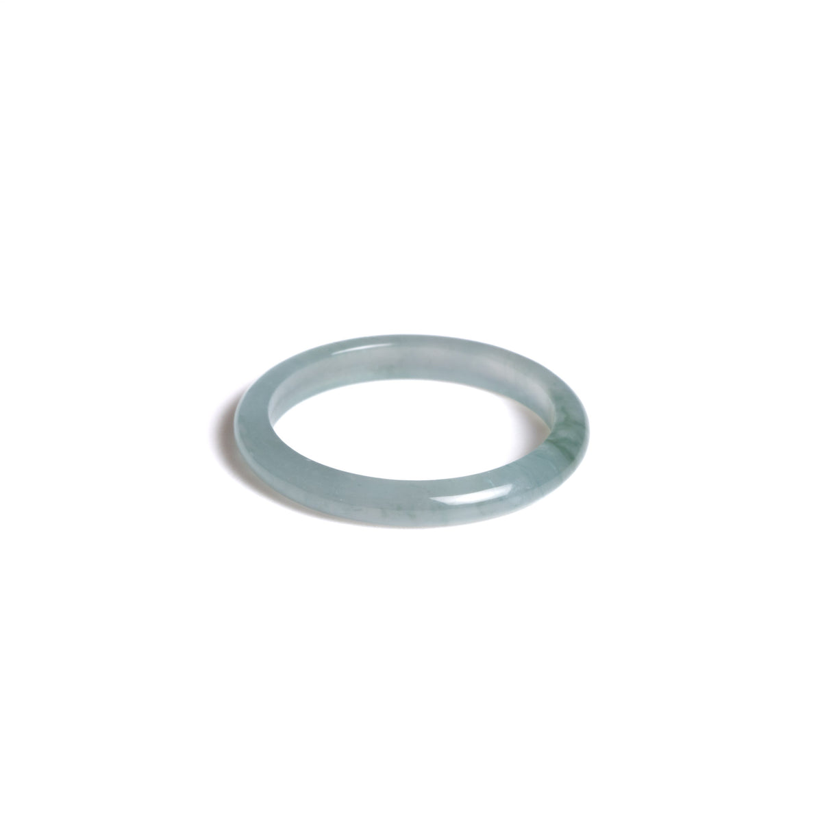 A highly translucent dainty jade ring of light green colour on a white background.