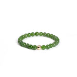 A bracelet featuring lustrous green Nephrite jade beads with a gold-filled accent on a white background.