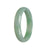 A close-up photo of a beautiful, icy apple green Jadeite bangle bracelet with a half moon shape, measuring 56mm in diameter. A stunning piece of jewelry from MAYS GEMS.
