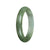 A close-up image of an untreated green Burmese jade bangle bracelet with a diameter of 60mm. The bracelet has a semi-round shape and is offered by MAYS GEMS.