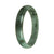 A half moon-shaped green jadeite jade bangle bracelet, showcasing its natural beauty.
