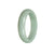A close-up photo of a beautiful green jade bangle with a half moon shape, measuring 57mm in diameter. The bangle has a genuine Type A certification and is made by MAYS™.