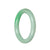 A close-up photo of a stunning emerald green Burma Jade bangle. The bangle is in the shape of a half moon and has a diameter of 58mm. It is certified Grade A and exhibits a beautiful, smooth texture. The rich green color of the jade is captivating and exudes elegance. Crafted with precision and quality, this bangle from MAYS™ is a true gemstone masterpiece.