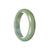 A close-up image of a beautiful half-moon shaped jadeite bangle in a vivid green color with delicate lavender swirls. The bangle has a smooth and polished surface, showcasing the natural beauty of the jadeite stone. The size of the bangle is 59mm, making it a perfect fit for most wrists. A stunning jewelry piece that exudes elegance and sophistication.