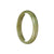 A close-up image of a real untreated brownish olive green jadeite bangle. The bangle is in the shape of a half moon and measures 59mm in diameter. It is being sold by MAYS GEMS.