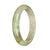 A close-up photo of a half-moon shaped jade bangle with a real natural white and light green color. The bangle has a smooth and polished surface, showcasing the beautiful patterns and markings of the jade stone.