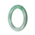 A close-up of a round, green jade bangle bracelet, with a smooth surface and a vibrant color.