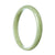 A close-up of a beautiful green Burma jade bangle bracelet, showcasing its smooth surface and half-moon shape. The bracelet is certified Grade A, indicating its high quality. Perfect for adding an elegant touch to any outfit.